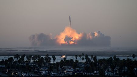 A photo of starship launching in the distance with massive plume of smoke