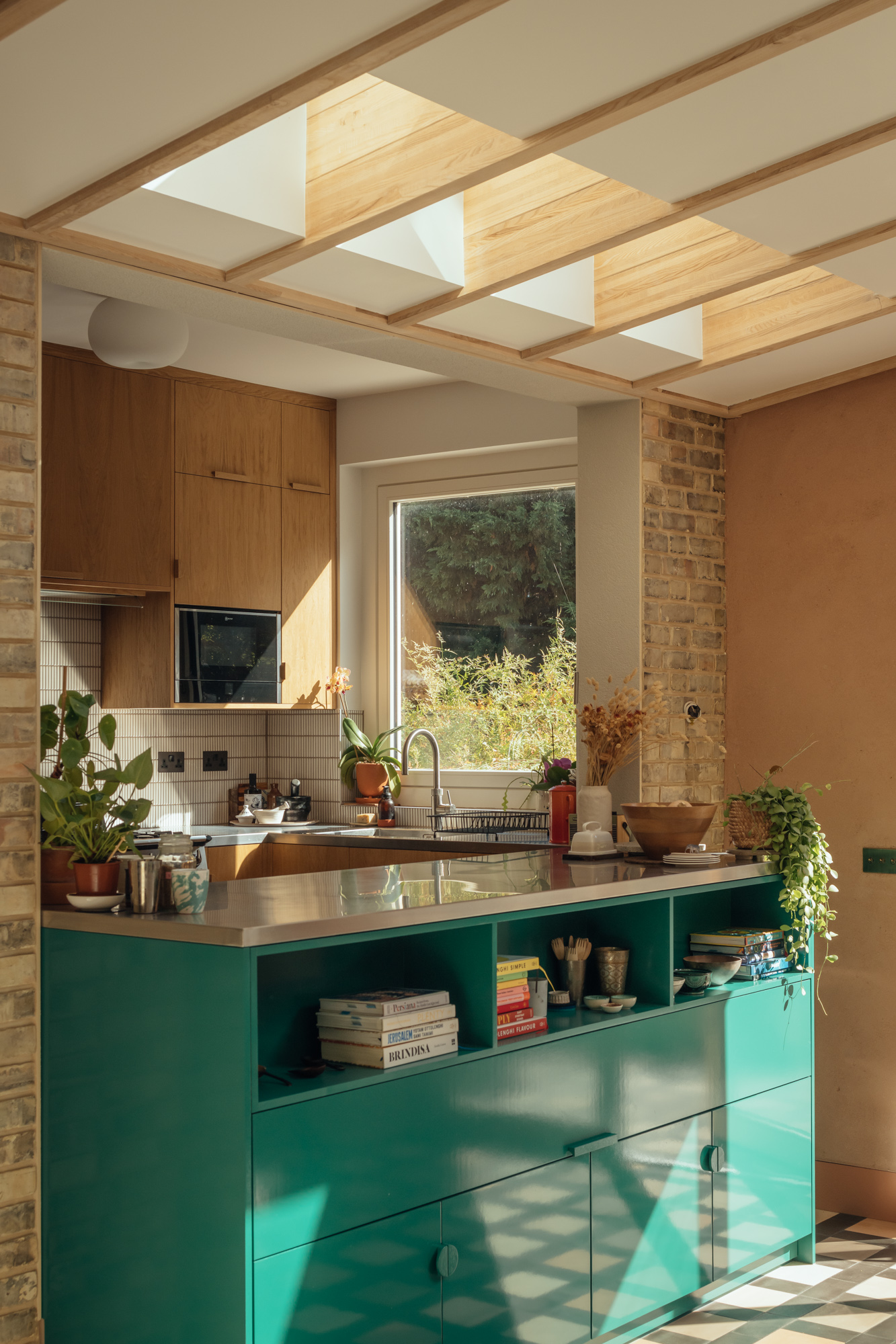 A kitchen with a green island, and roof lights above