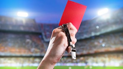 A soccer referee holds up a red card penalty.