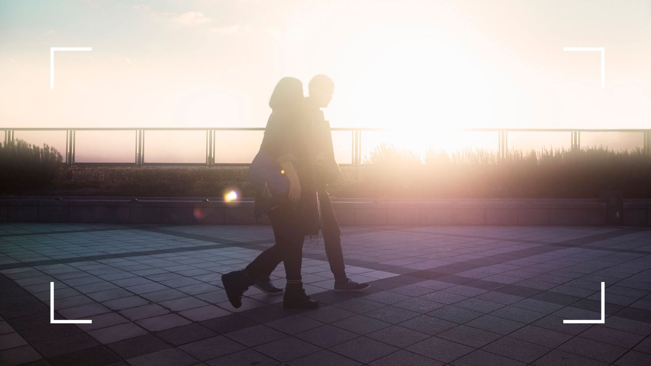 Woman and man walking after dinner in the evening together against the backdrop of sun setting