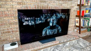 LG B2 OLED TV shown against a brick wall in a living room