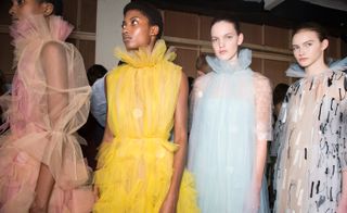 Models wear tulle sheer dresses in pink, yellow and blue, with high-neck bloom collars