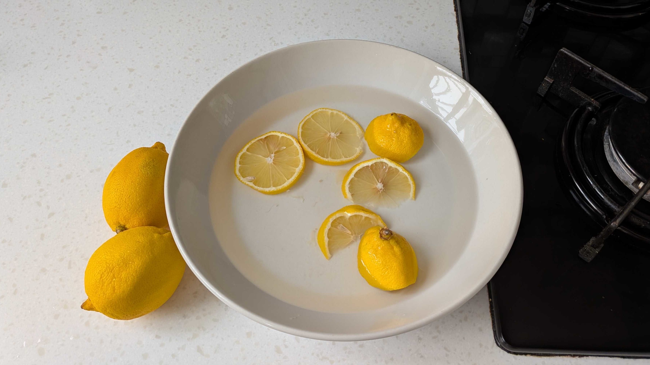 Lemons next to bowl with slices in water