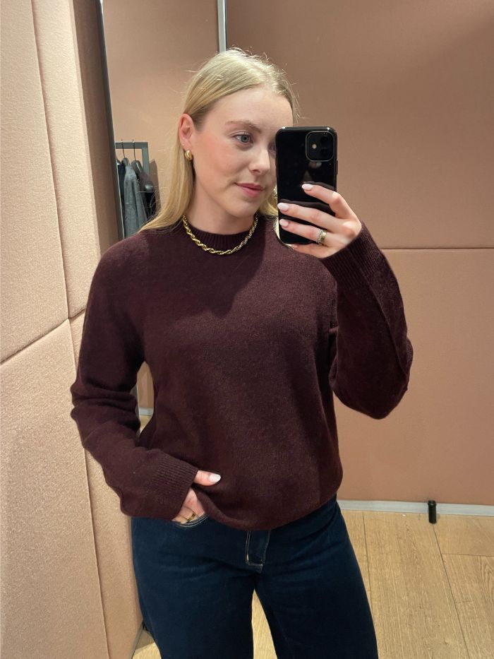 Woman wears burgundy cashmere jumper and blue jeans