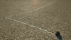 A view of a sailing rock with its track featuring a sharp bend on Racetrack Playa.