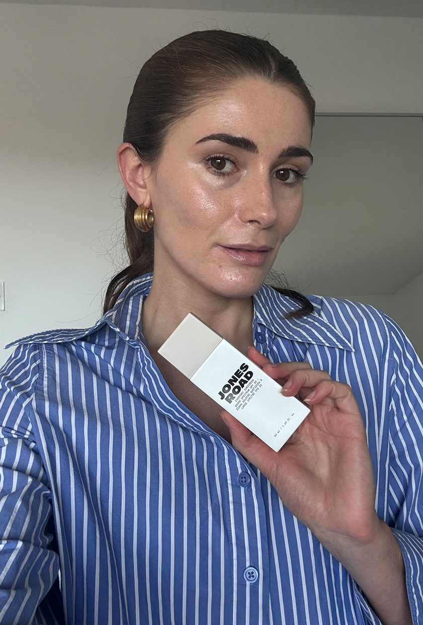 Eleanor, Jones Road Everyday Sunscreen'i tutarak kumlu gölgede selfie çekiyor