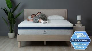 Woman sleeping on a Helix mattress on a wooden base, with a plant and lamp in the room