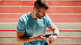 Disappointed man checking sports watch at running track