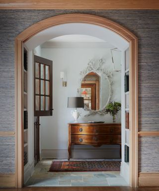 A coastal style entryway with a large arched doorway and an antique console table