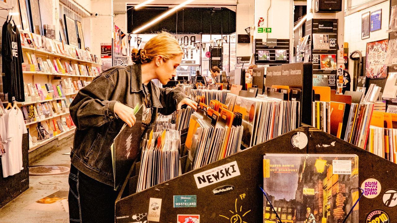 Rough Trade shop with vinyl LPs racked and a young woman browsing 