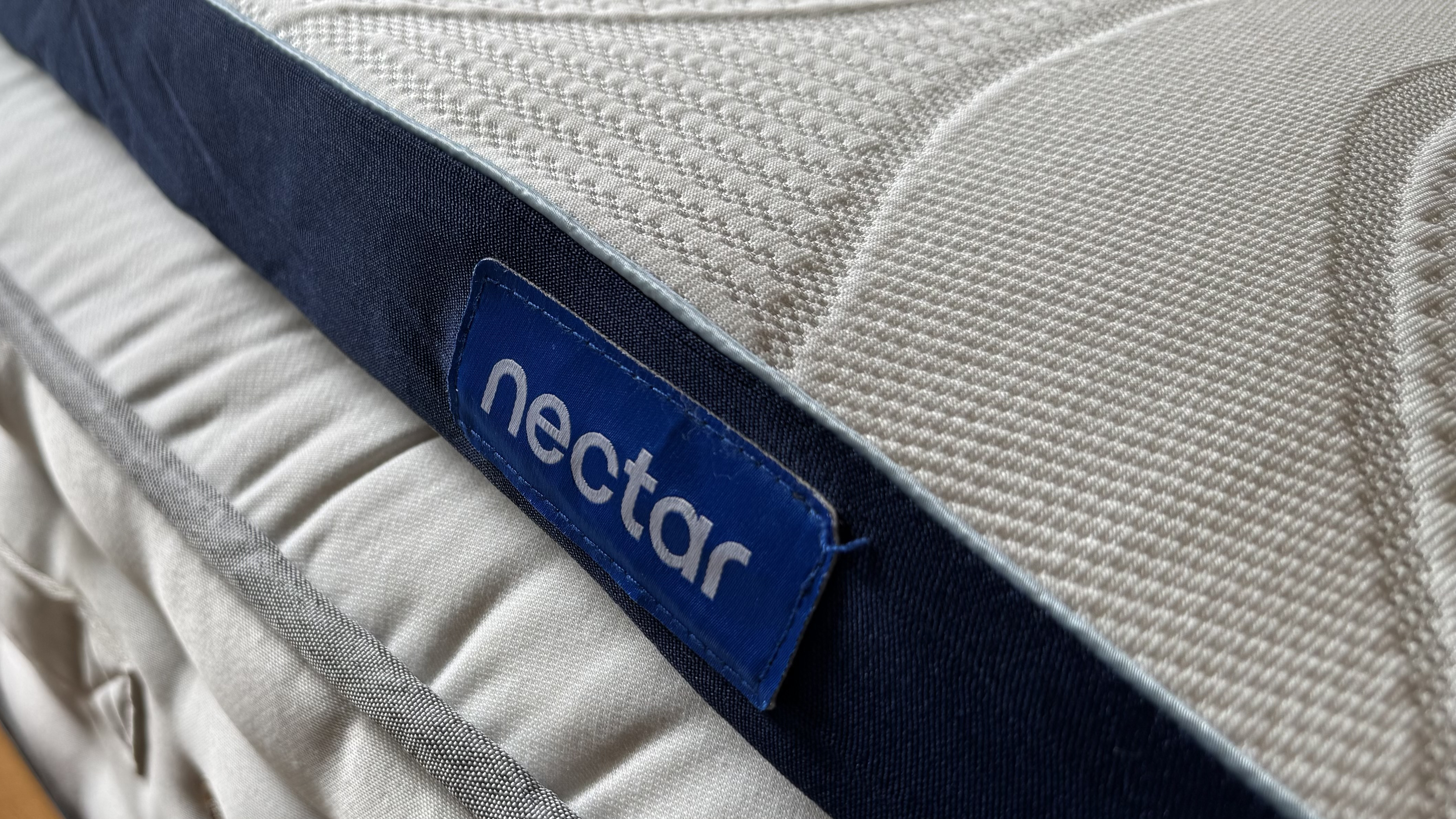 The foot of our tester's full-size Nectar mattress topper, as seen on top of a hybrid mattress.