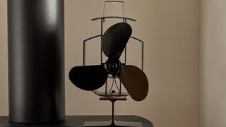 A three-bladed stove fan made by VonHaus, positioned on top of a stove