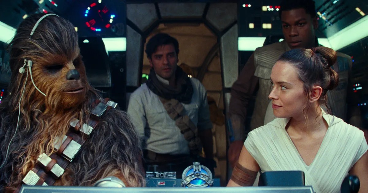 Rey smiles at Chewbacca in the cockpit of the Millennium Falcon, while Poe Dameron and Finn stand in the background.