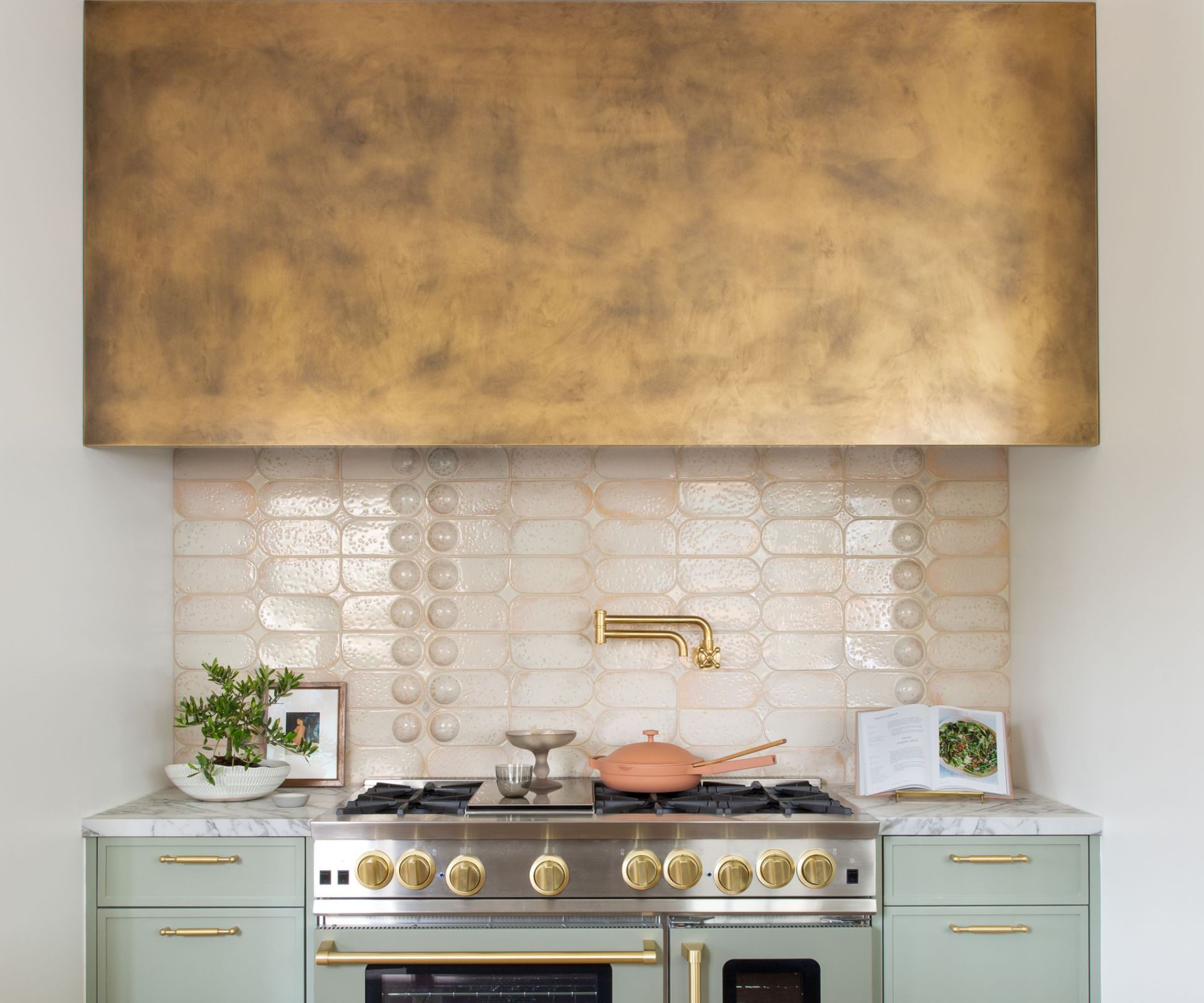 burnished gold cooker hood and cabinets and pale green range cooker