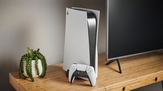 A Playstation 5 and controller on a TV stand next to a TV