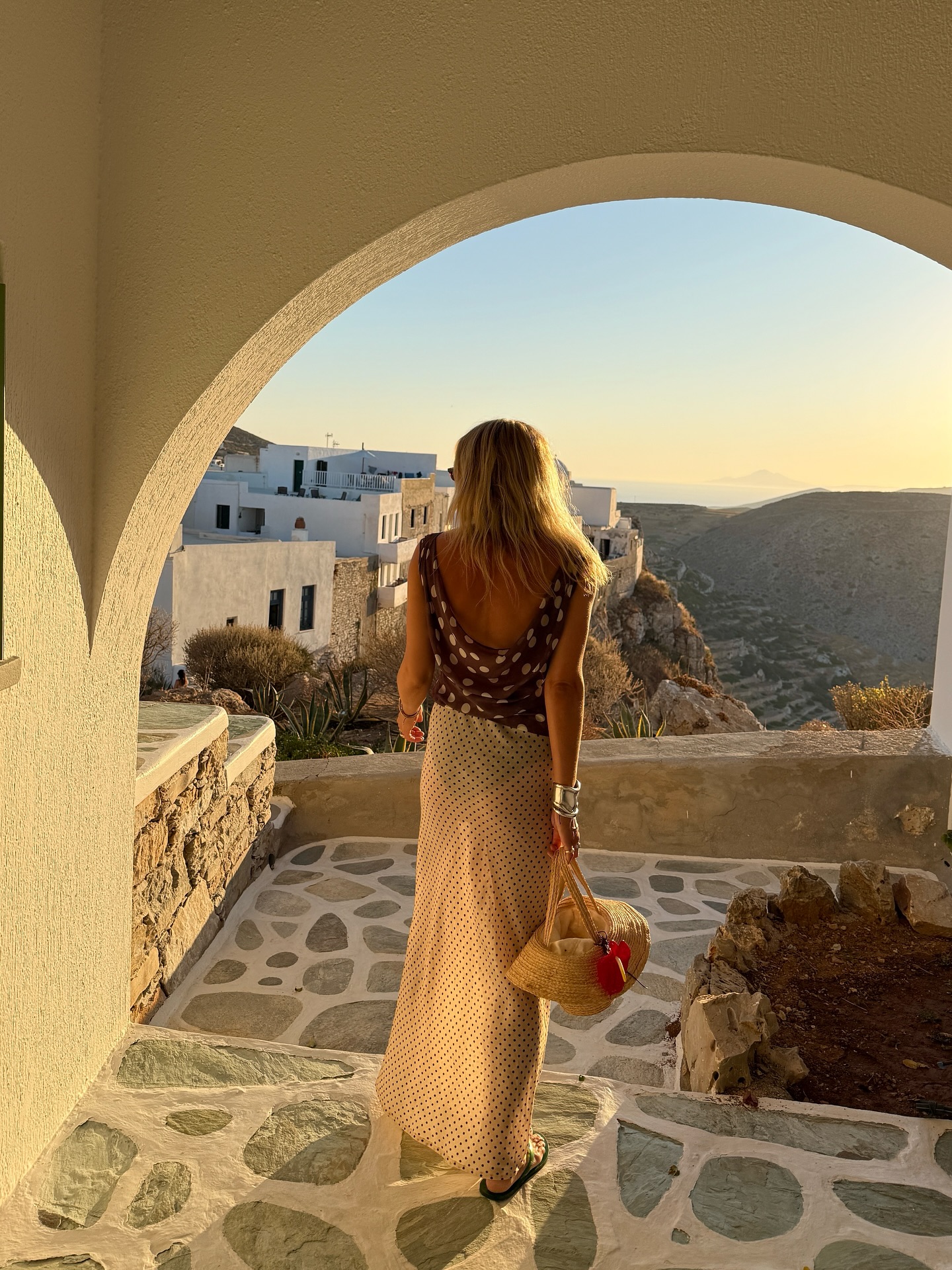 An image of @lucywilliams02 wearing a cowl-neck brown polka-dot top with a sheer polka-dot skirt while in Greece.