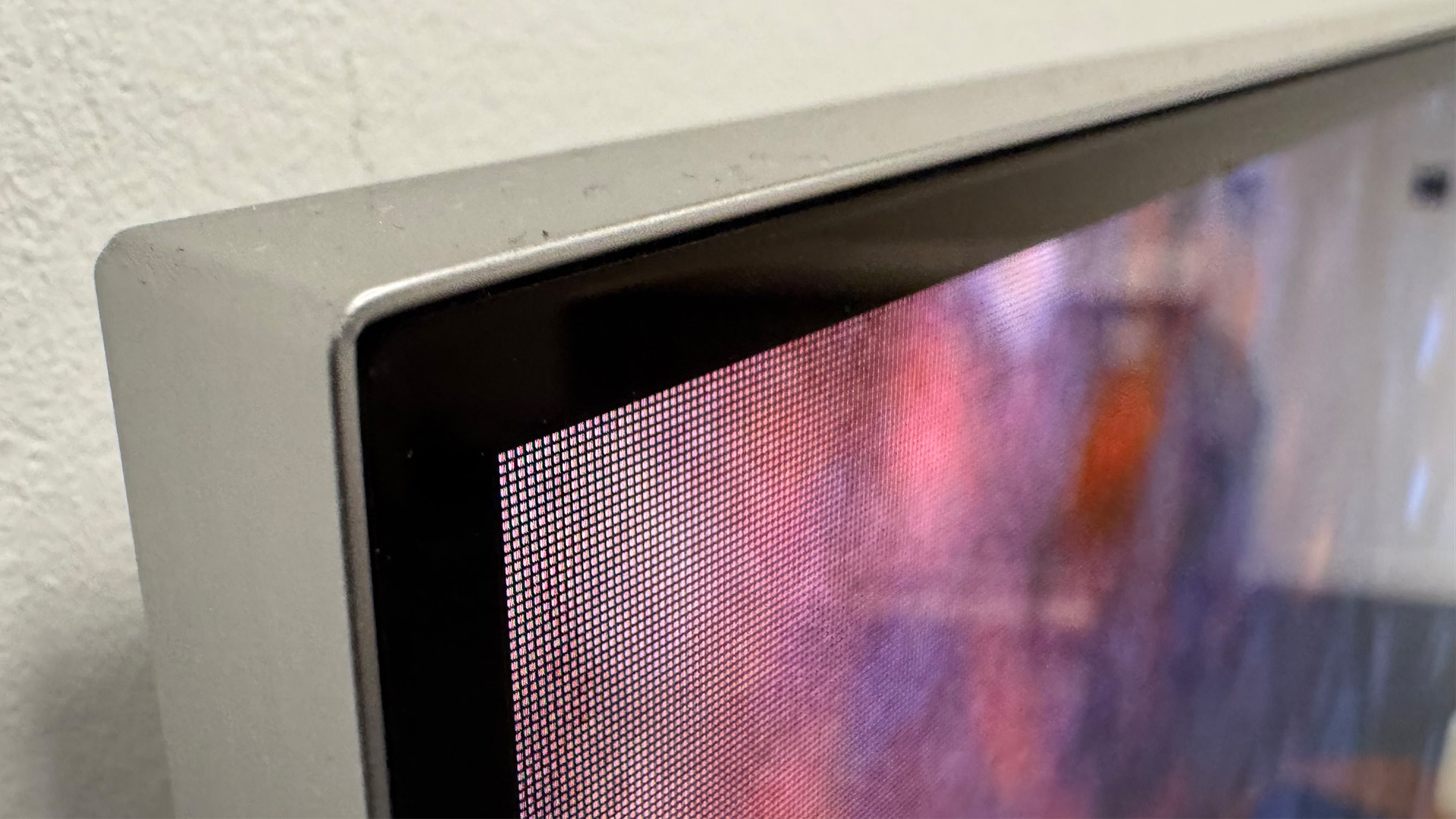 The 65-inch LG M5 OLED TV pictured mounted to a grey wall.