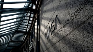 the words "nasa national aeronauts and space administration" are etched into the stone facade of a building under a glass awning