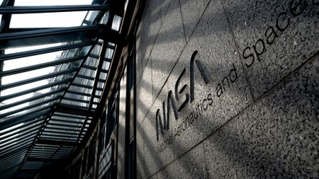 the words "nasa national aeronauts and space administration" are etched into the stone facade of a building under a glass awning