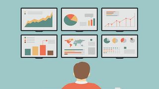 Man sitting at a desk looking at six monitors displaying graphs