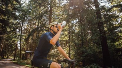 Image shows a rider drinking from a water bottle. 
