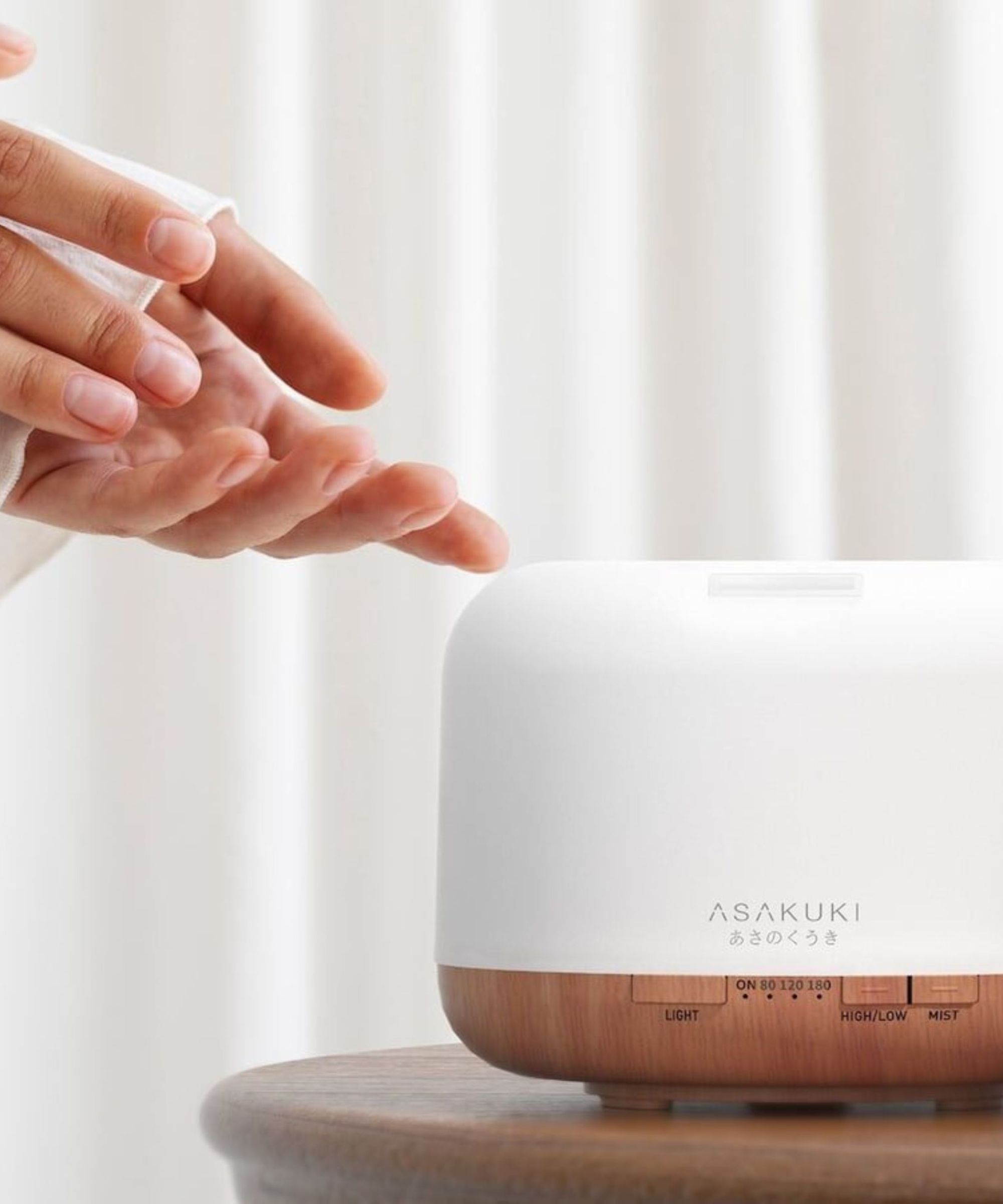 A hand switching on the ASAKUKI Portable Essential Oil Diffuser.