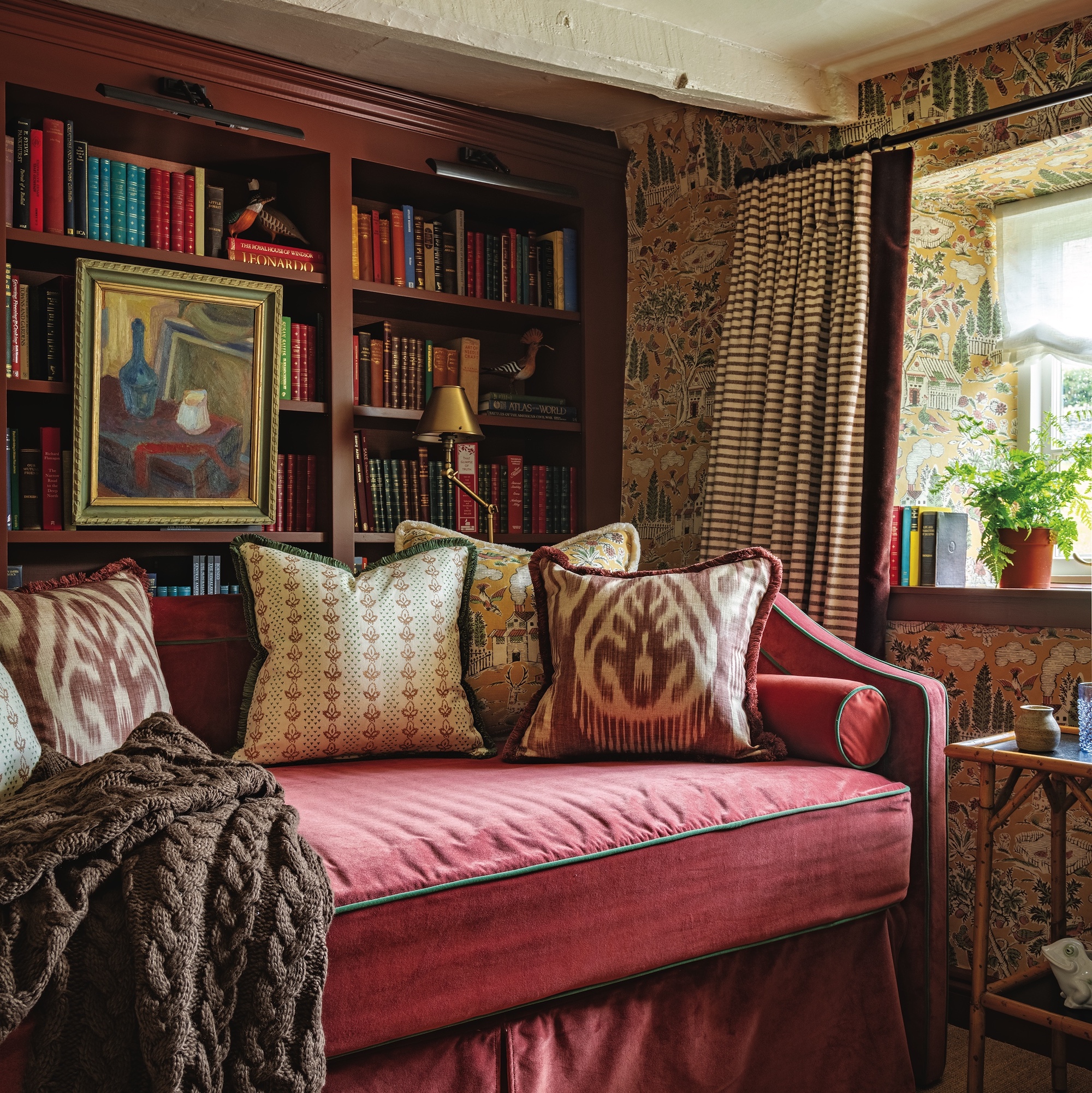 pink daybed with cushions in front of wooden bookshelves