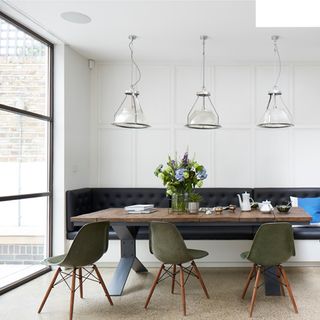 dinning area with white wall wooden dinning table with chairs and seat and overhead lamps