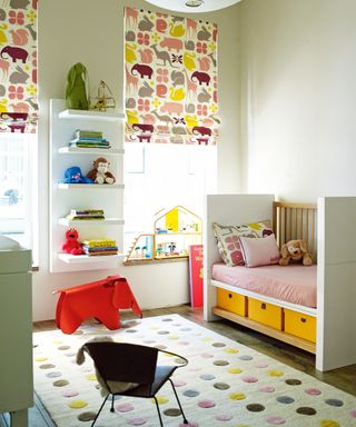 A neutral girls' nursery with pink and yellow bed, and pink and yellow animal print blind design.