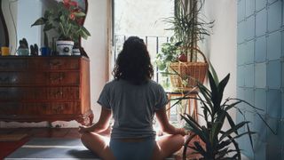 View Of Woman Meditating While Sitting At Home - stock photo