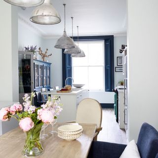 A dining room looking through to kitchen with matching metal pendant lights