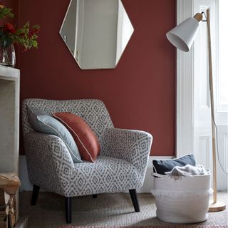 red wall with mirror and armchair with cushion