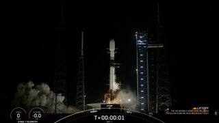 a black-and-white spacex falcon 9 rocket launches into a night sky.