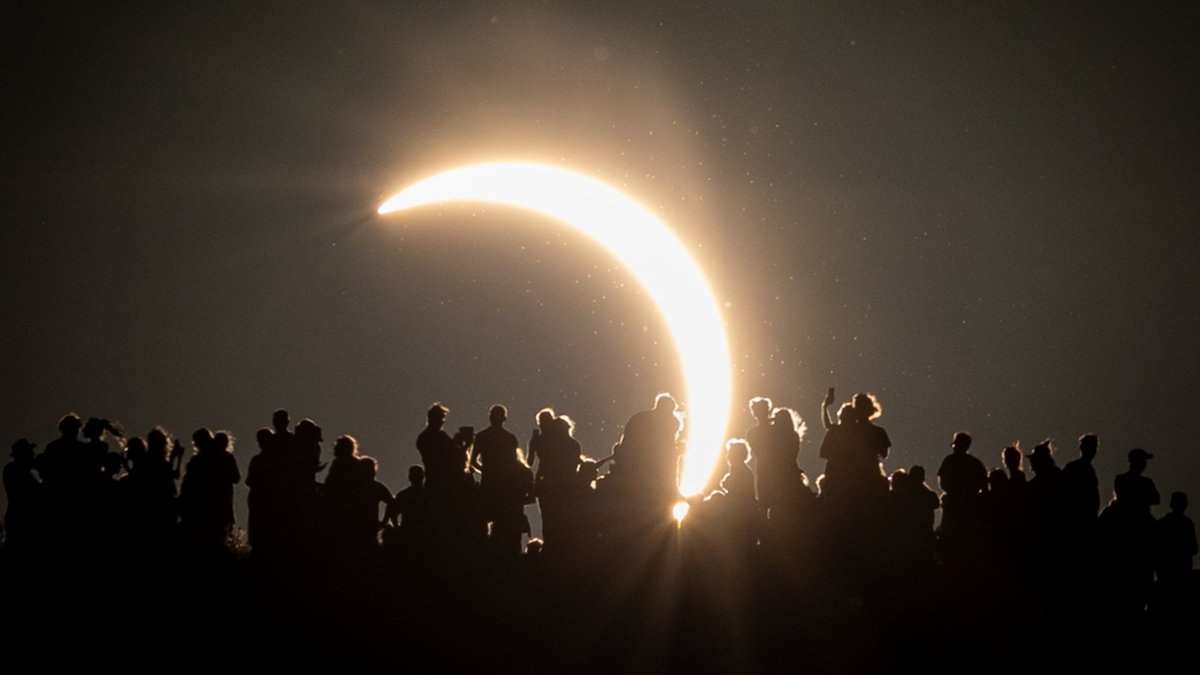 GLASTONBURY, ENGLAND - AUGUST 12: People view the partial solar eclipse besides the historic St. Michael's Church tower, a Grade I listed building at the top of Glastonbury Tor on August 12, 2026 in Glastonbury, England. The partial solar eclipse is the most coverage during an eclipse viewed from the UK since 1999, with the moon covering 90-96% of the sun. (Photo by Matt Cardy/Getty Images)