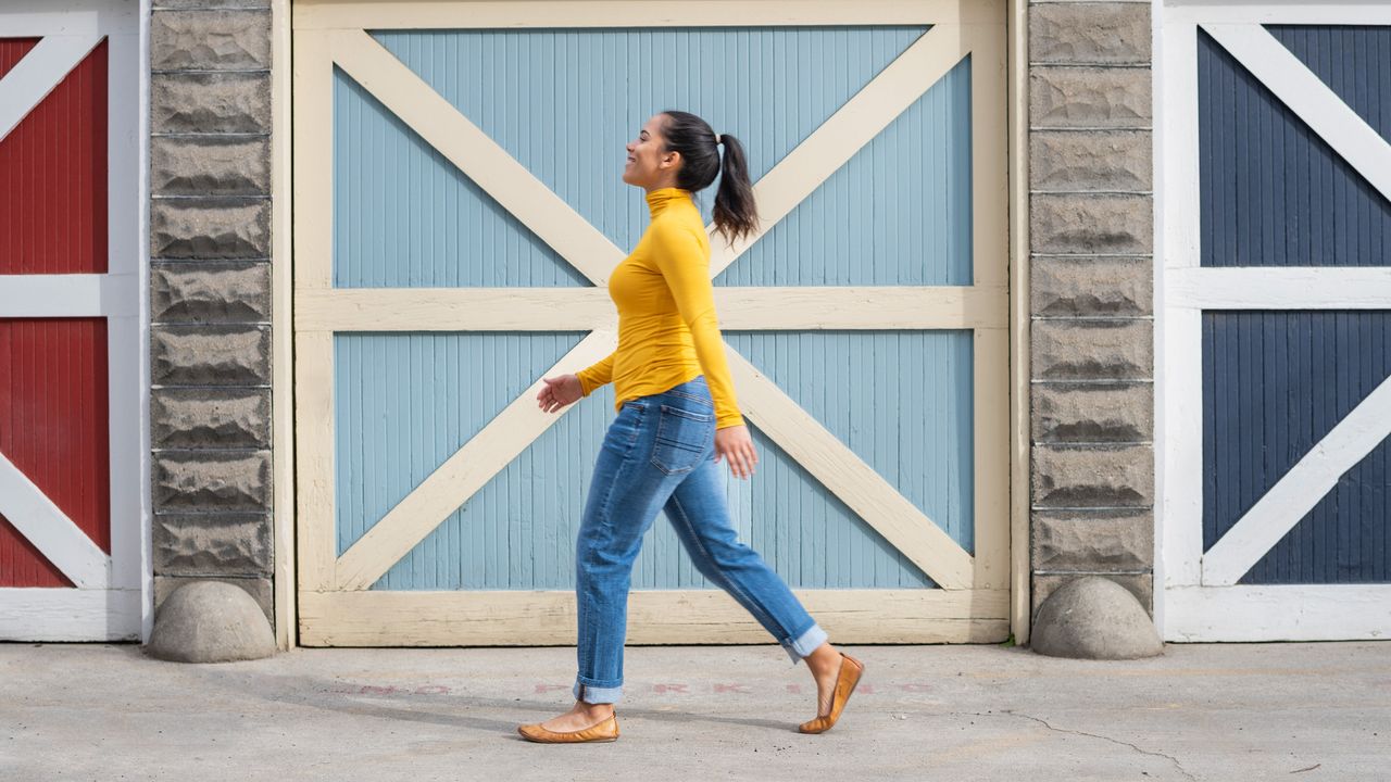 A smiling woman walking in front of colorful beach hut doors