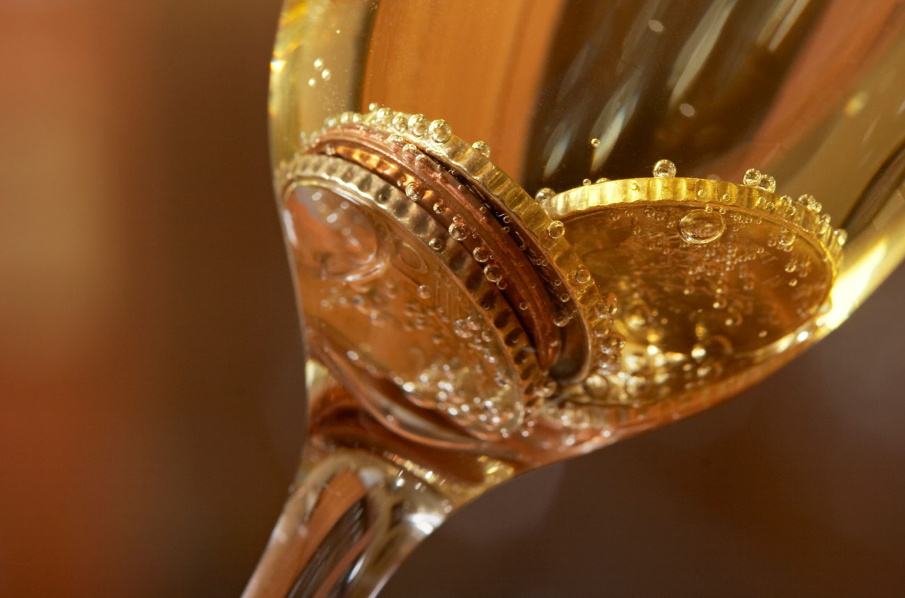 Coins in a glass of sparkling wine