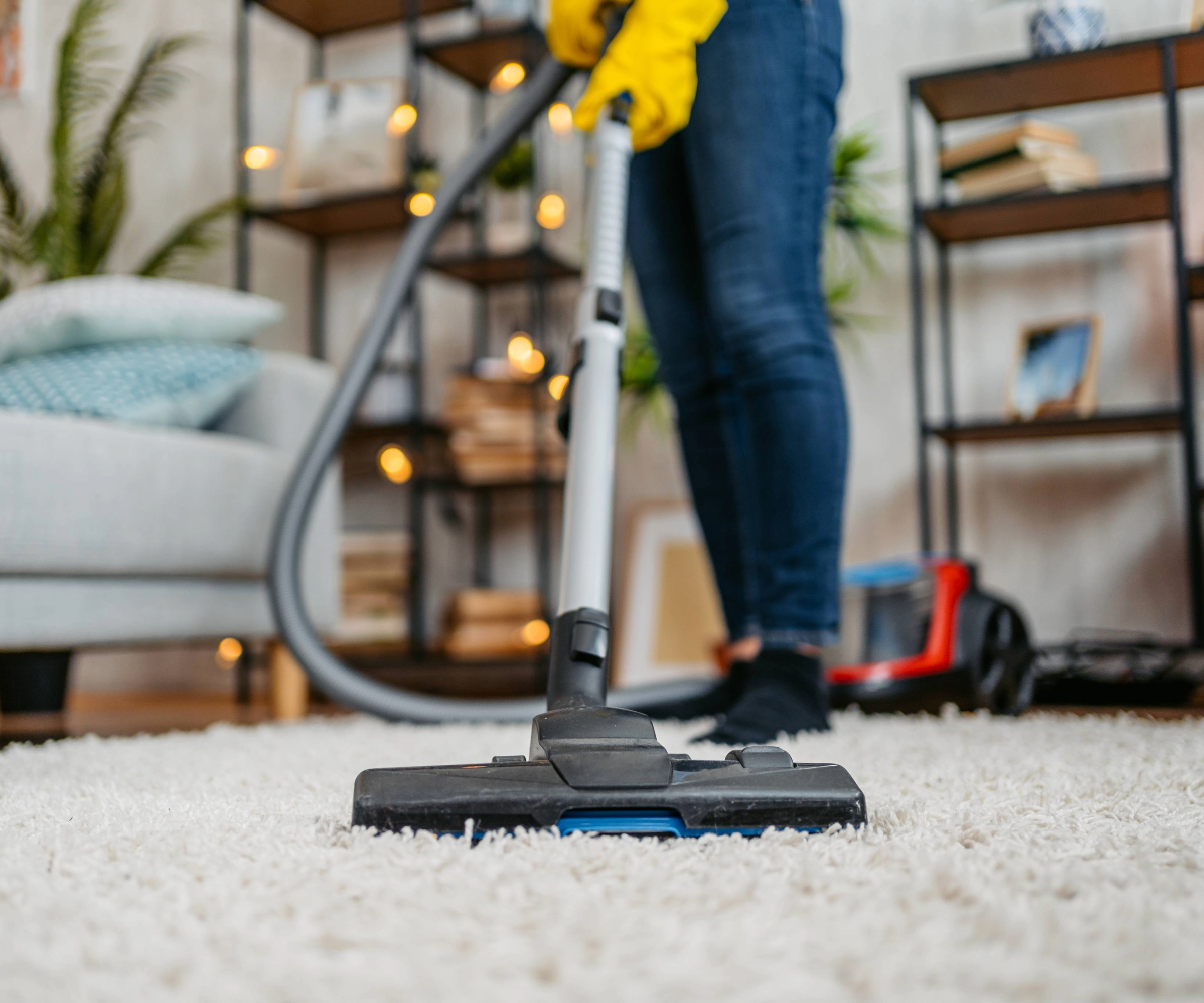 Person vacuuming a rug wearing rubber gloves