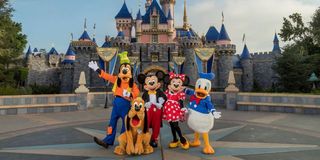 Goofy, Pluto, Mickey, Minnie and Donald Duck stand in front of Sleeping Beauty's Disneyland castle.