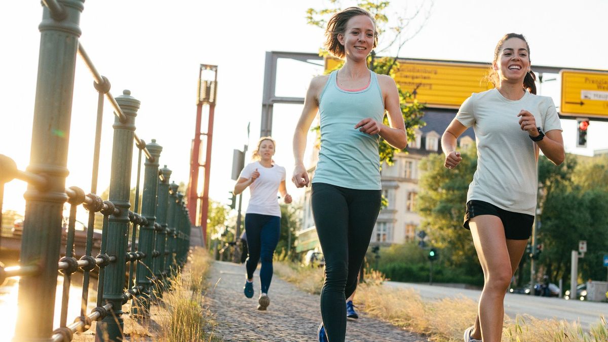 Three women running by a canal