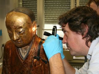 A gold-painted papier-mâché statue of the Buddha contained the mummified remains of an ancient Buddhist monk who lived during the 11th or 12th century. Here, a researcher inspects the statue.