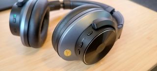 A pair of black and grey OneOdio A10 headphones sitting on a wooden desk