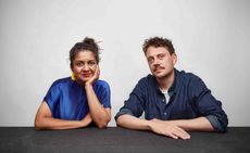 Portrait of Superflux co-founders Anab Jain and Jon Adern sitting behind a table with a grey background