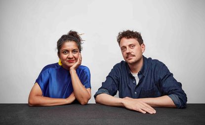 Portrait of Superflux co-founders Anab Jain and Jon Adern sitting behind a table with a grey background