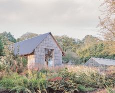 The Apple House, timber building with shingles and pitched roof set among wildflower fields