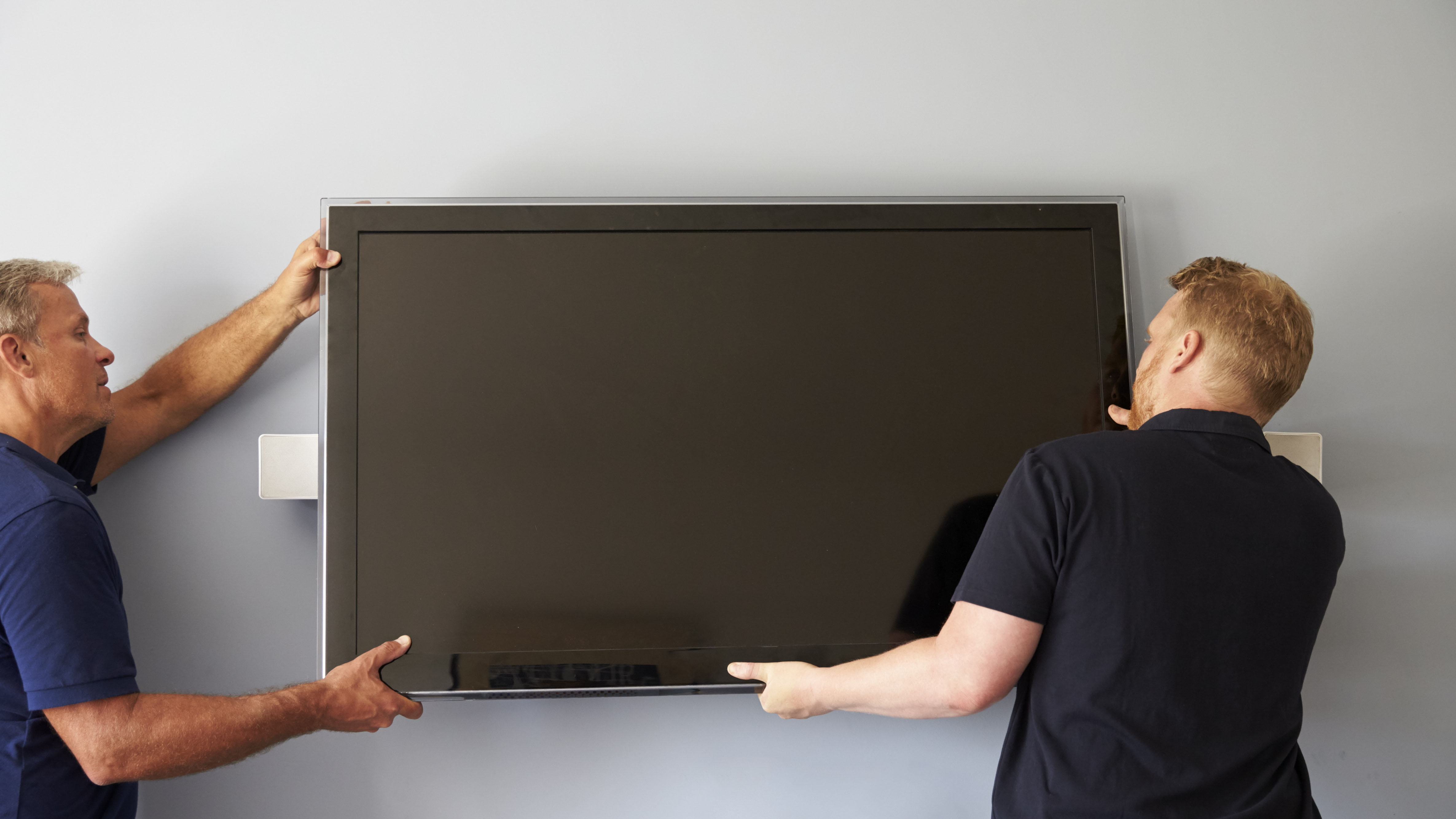 Two men mounting a TV on a wall