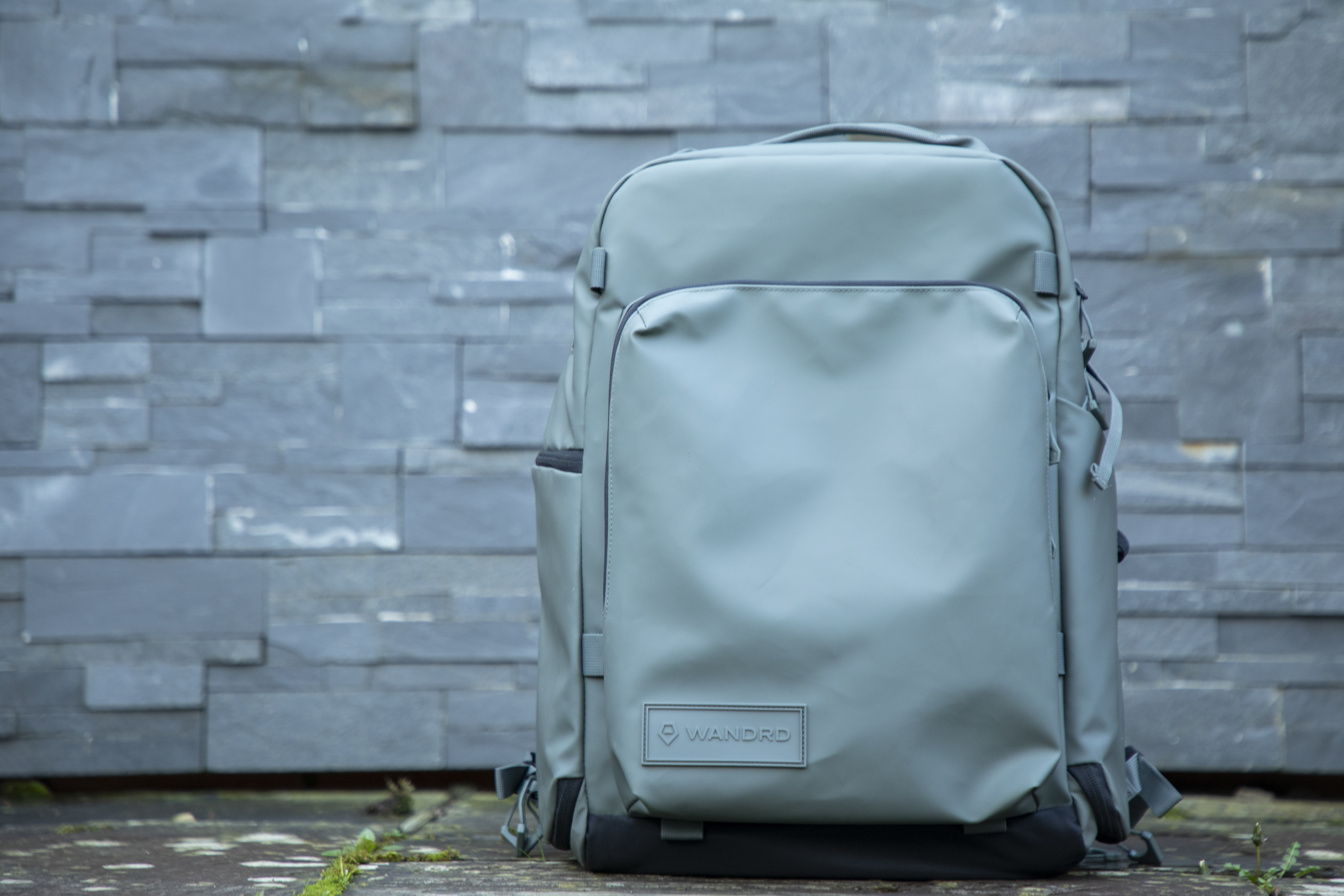 light green camera backpacks against grey brickwork background