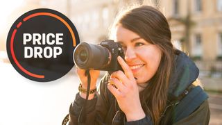 A female photographer using the Sony A7 III in a brightly lit street at sundown, with the text "Price drop"