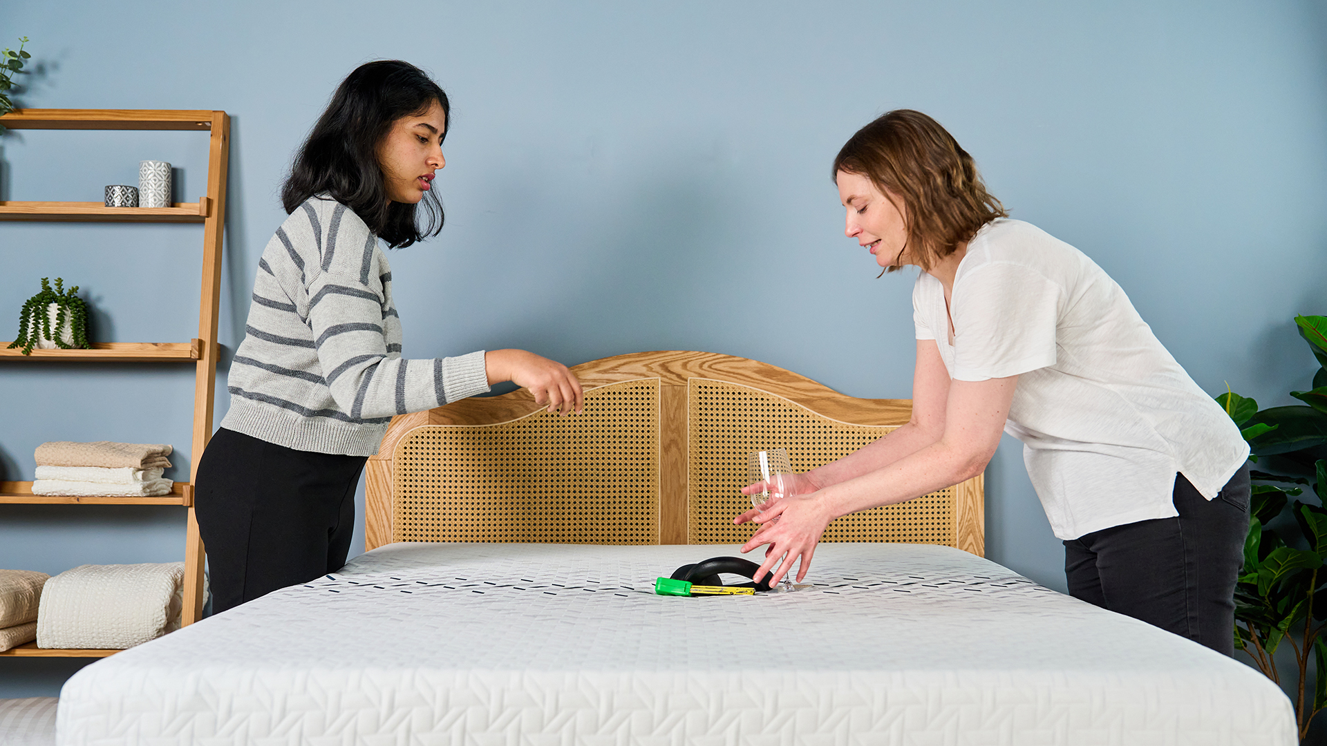 Two Tom's Guide mattress testers dropping a weight next to a wine glass to measure how well the Nectar Ultra Hybrid performs in motion isolation tests