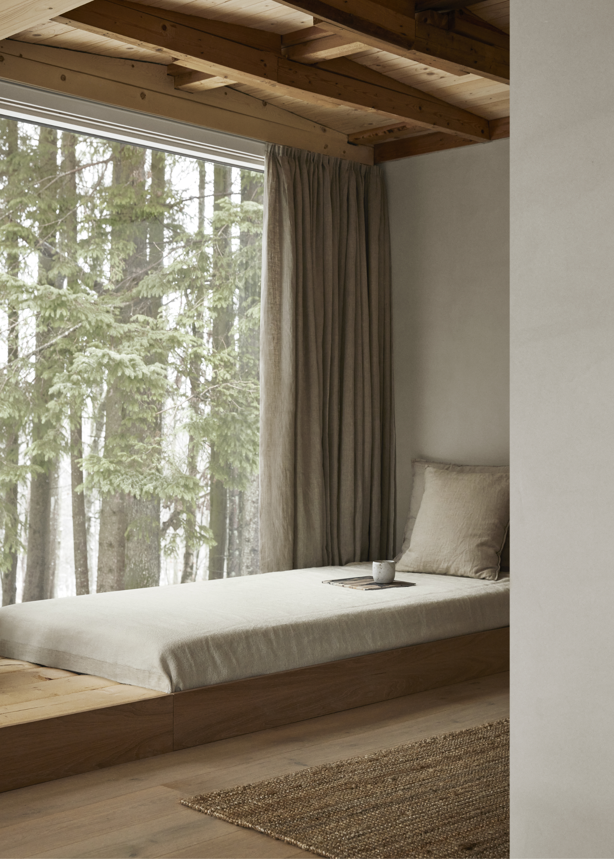 A floor bed by a window sill with the view of trees