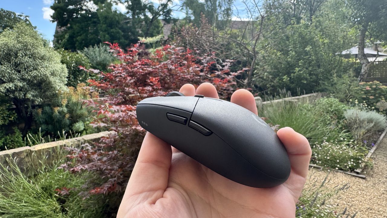 Logitech G305 X Superlight gaming mouse, held in a hand outside